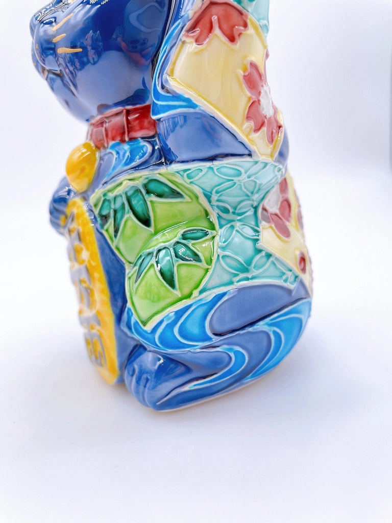 Japanese Kiyomizu-style Maneki-neko (lucky cat) with cross-colored dark blue background and floral pattern.