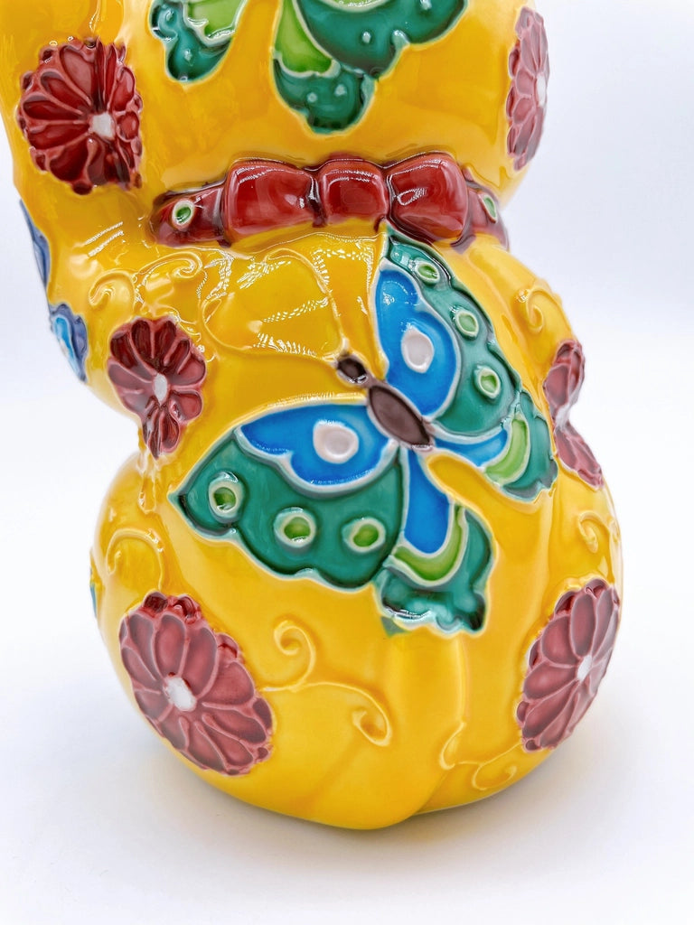 Japanese Kiyomizu-style lucky cat saucer with a yellow background and floral design.